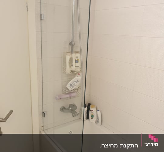 מחיצת זכוכית במקלחת עם ברז ומוצרים